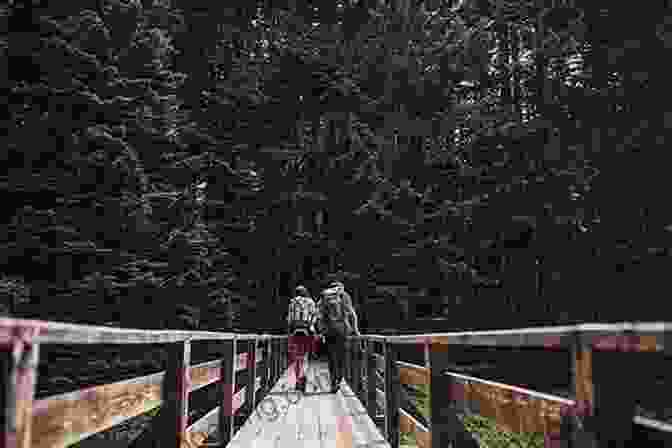 Hikers Crossing A Wooden Bridge Surrounded By Lush Greenery On The Mohican Trail. Ohio Backpacking Loops: A Guide To 14 Backpack Trails In The Buckeye State